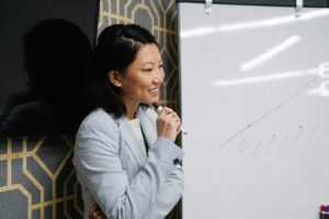 A professional from a digital marketing agency in Singapore presenting campaign performance trends on a whiteboard.