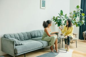Two women having a professional discussion in a modern office lounge, demonstrating the importance of collaboration in the Client Success Framework.