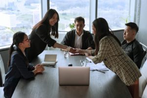 A diverse team of professionals shaking hands during a meeting in a modern office, symbolising collaboration, partnership, and trust in a B2B marketing environment.