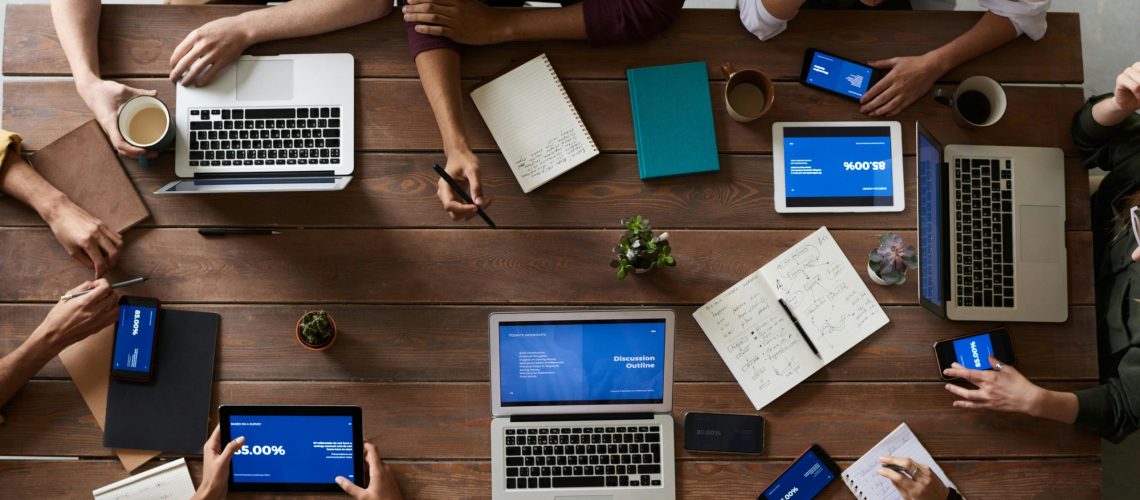 B2B marketing team collaborating during a strategy meeting with laptops and digital devices on a wooden table.